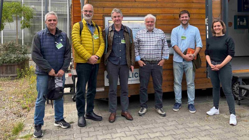 Gruppenfoto vor einem BioökonomieMOBIL: Vertreter:innen aus Forschung und Praxis von BioökonomieREVIER und der Kooperative Aapresid tauschen sich über nachhaltige Wirtschaftsformen und regionale Bioökonomie-Konzepte aus.