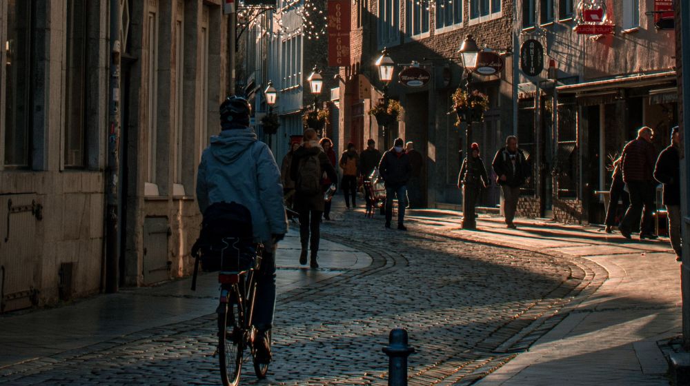 Das Bild zeigt eine Radfahrerin in der Aachener Innenstadt auf der Annastraße. Es hängt bereits die Weihnachtsbeleuchtung. Die Straße ist mit Kopfsteinpflaster gepflastert.